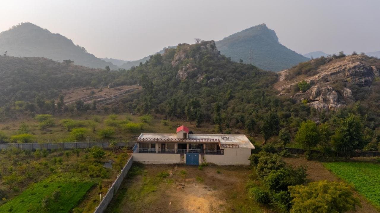 The villa seen from above, among green fields and rocky hills