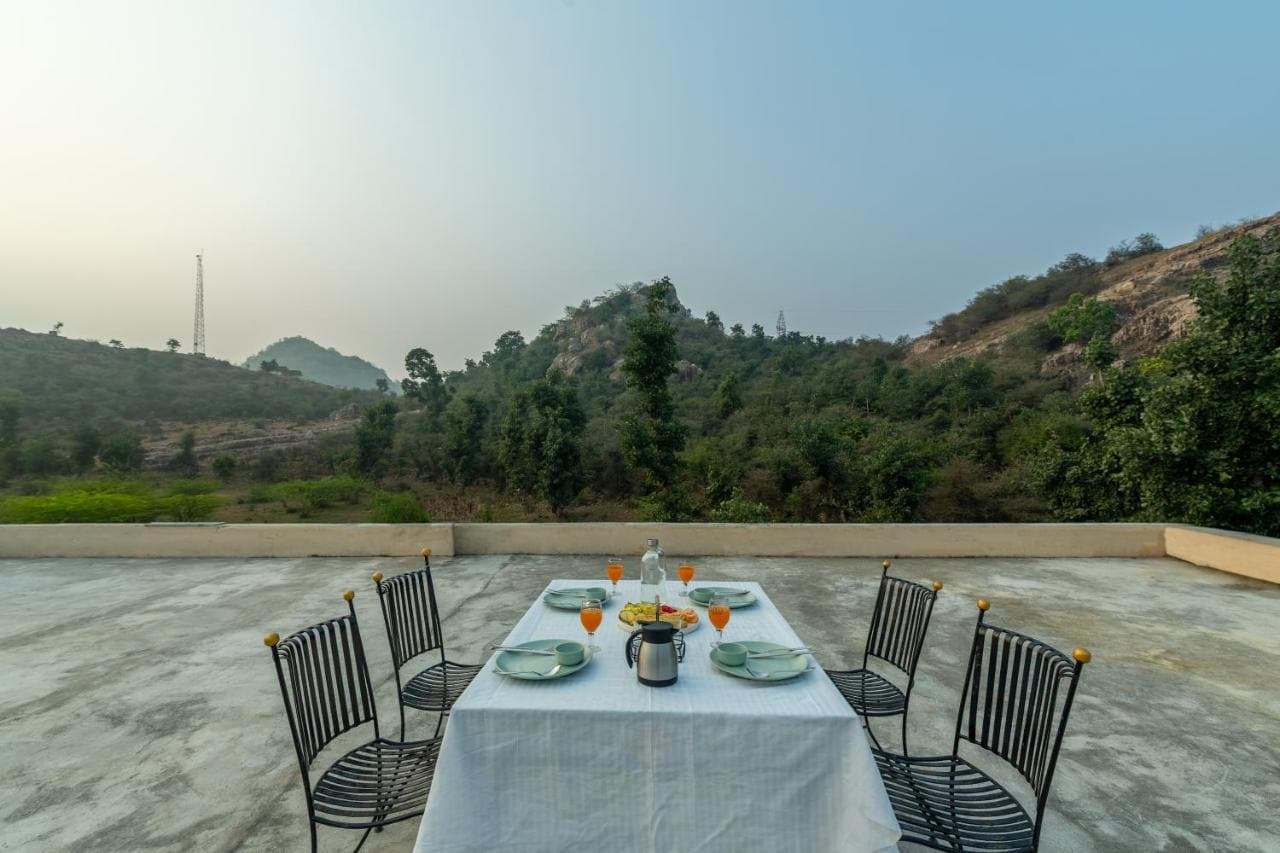 Breakfast table set on the rooftop terrace with forested hills behind